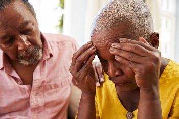 An elderly African woman receiving support from a caregiver