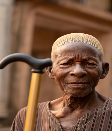 An elderly African man holding a cane