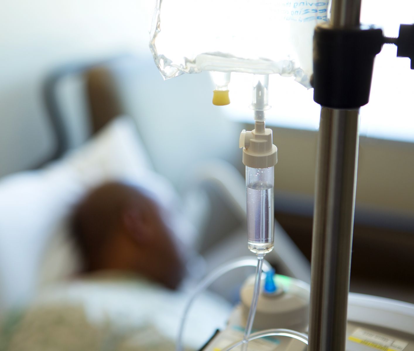 A black patient receiving intravenous therapy in a hospital bed