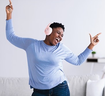 A black woman dancing to music from a headphone