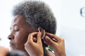 An elderly African woman being fitted with a hearing aid