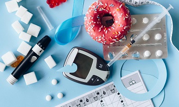 A blue ribbon, blood sugar meter, medication, junk food and sugar cubes