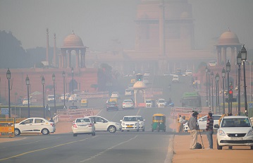 A road with light traffic of cars and tricycles and heavily polluted air