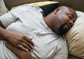 A middle-aged black man sleeping with his mouth slightly open.