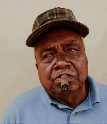 An elderly African man with a cigar in his mouth