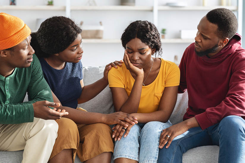 Group of black young adults seated and supporting a peer 