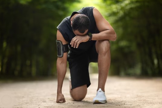 Black sportsman feeling unwell while jugging in a park.