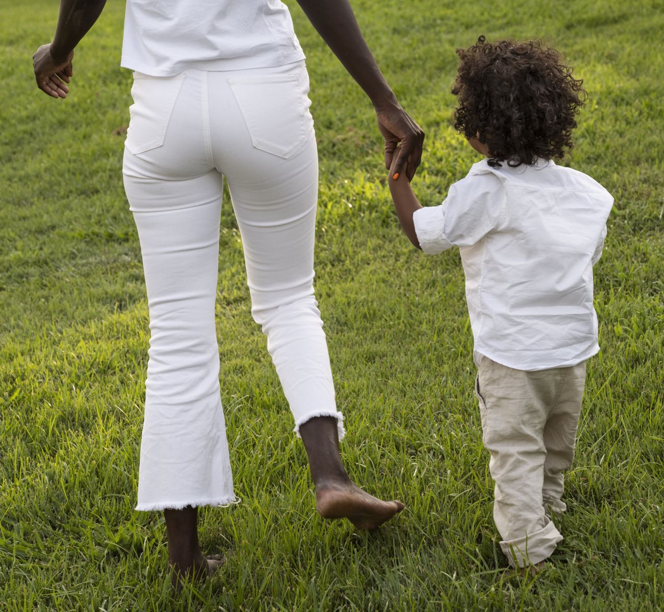 Black woman and child walking in an open field