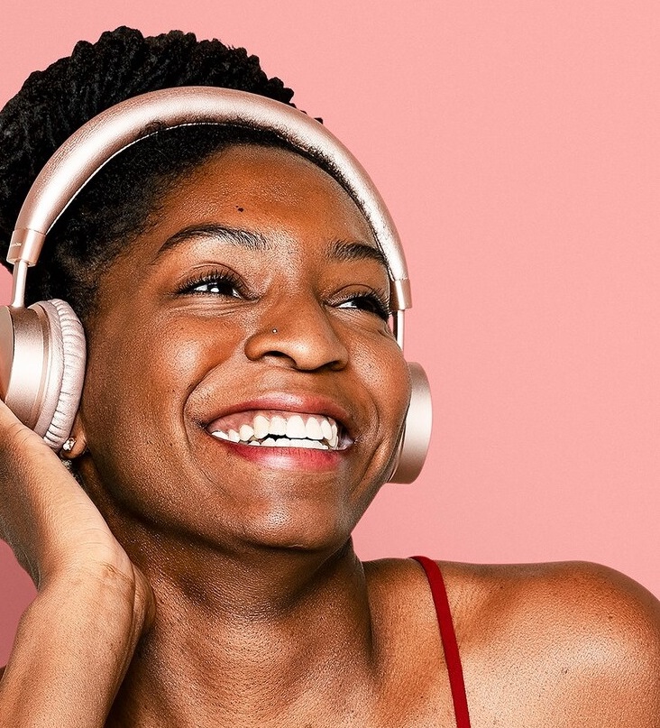 Cheerful black lady listening to music through a headphone