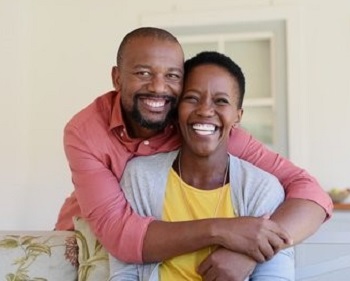 Happy looking black couple in midlife, embracing, heads side-by-side and smiling