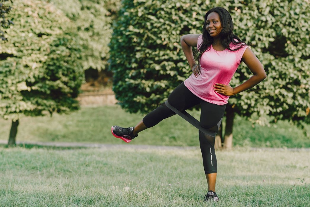 Young black lady doing leg strengthening exercise with a thigh band