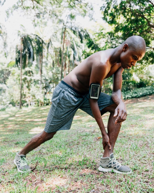 An adult  black exercising outdoor with a wearable smartphone on the right arm  