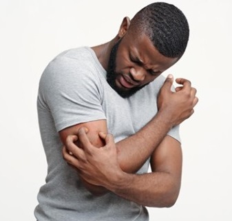 Young blackman scratching his itching right arm with his left hand