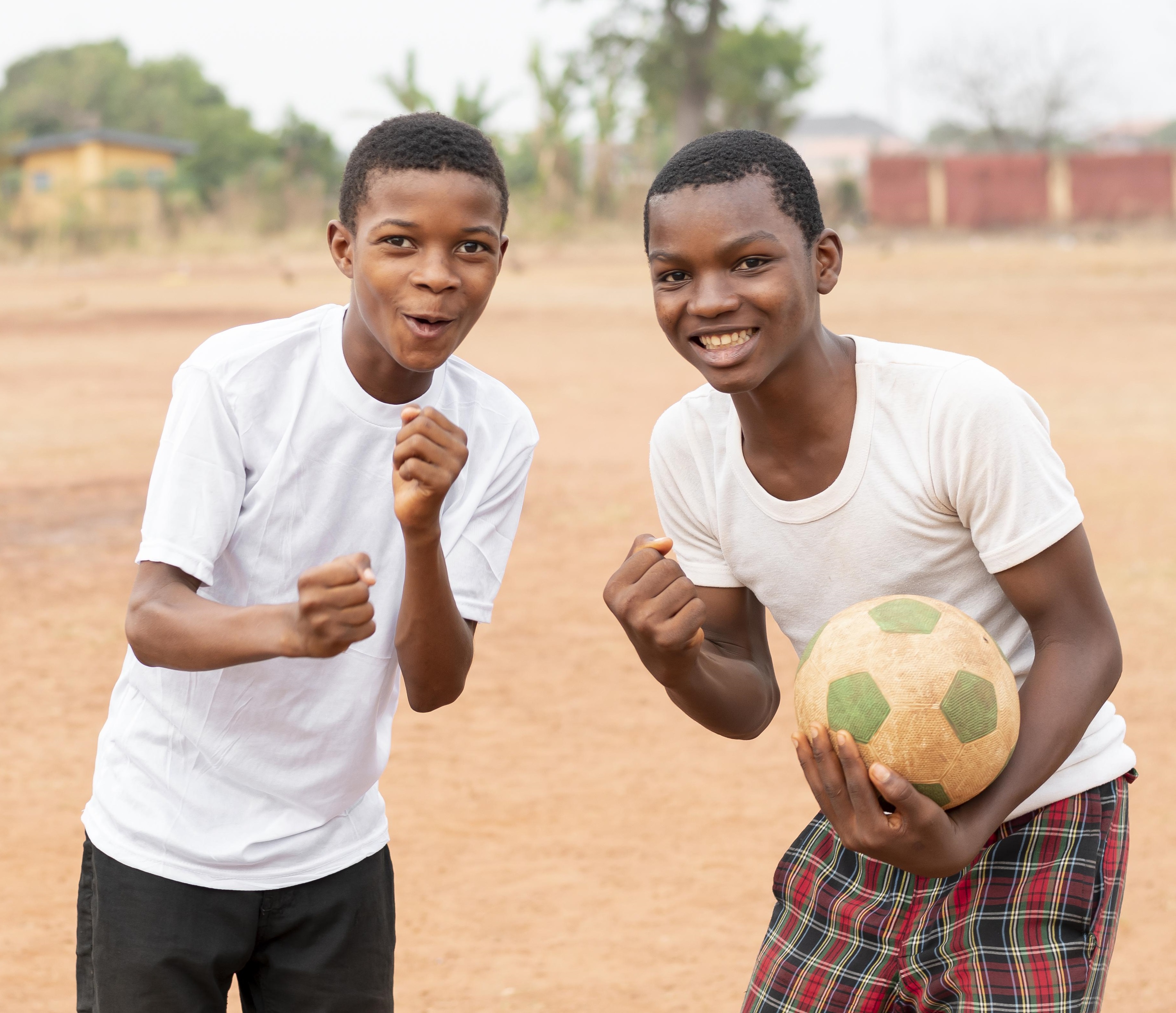 African boys posing outdoors with football in hand
