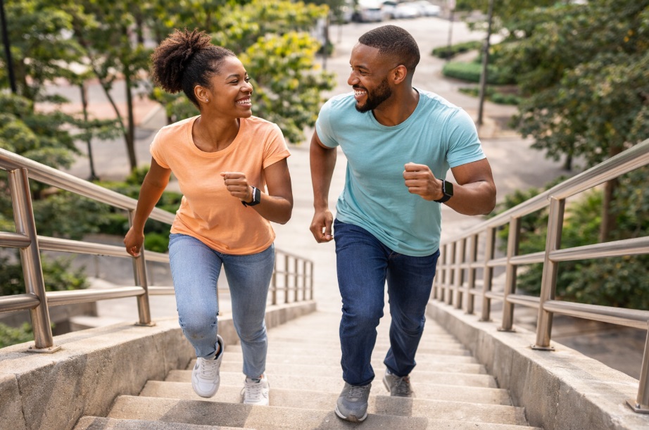 A black couple climbing a staircase together vigorously