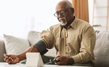 An elderly black man checking his blood pressure at home